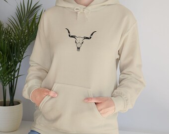 Può includere: Felpa con cappuccio beige con tasca a marsupio e coulisse. La parte anteriore presenta una grafica nera di un teschio di toro. La felpa è realizzata in un materiale morbido e confortevole.