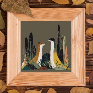 May include: A framed cross-stitch artwork featuring two stylized animals amidst a forest scene. The animals have long necks and are colored in shades of brown, white, and yellow. The artwork is set against a muted green background and framed in light wood.