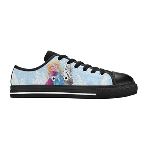 May include: Low-top canvas sneakers featuring a light blue background with a winter scene and characters from a popular animated film. The sneakers have black laces, a black toe cap, and a black sole with a white stripe.