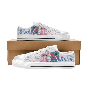 Pu&ograve; includere: Scarpe da ginnastica in tela bianca con un design a cartoni animati di Stitch e Angel. Le scarpe hanno una suola in gomma bianca e la parola "Stitch" stampata sul lato. Il design include cuori e uno sfondo azzurro.
