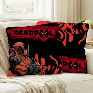Może przedstawiać: Dwie kwadratowe poduszki z postacią Deadpoola. Jedna poduszka przedstawia Deadpoola ze skrzyżowanymi ramionami i mieczami. Druga poduszka ma napis "DEADPOOL" w czerwonych literach na czarnym tle.