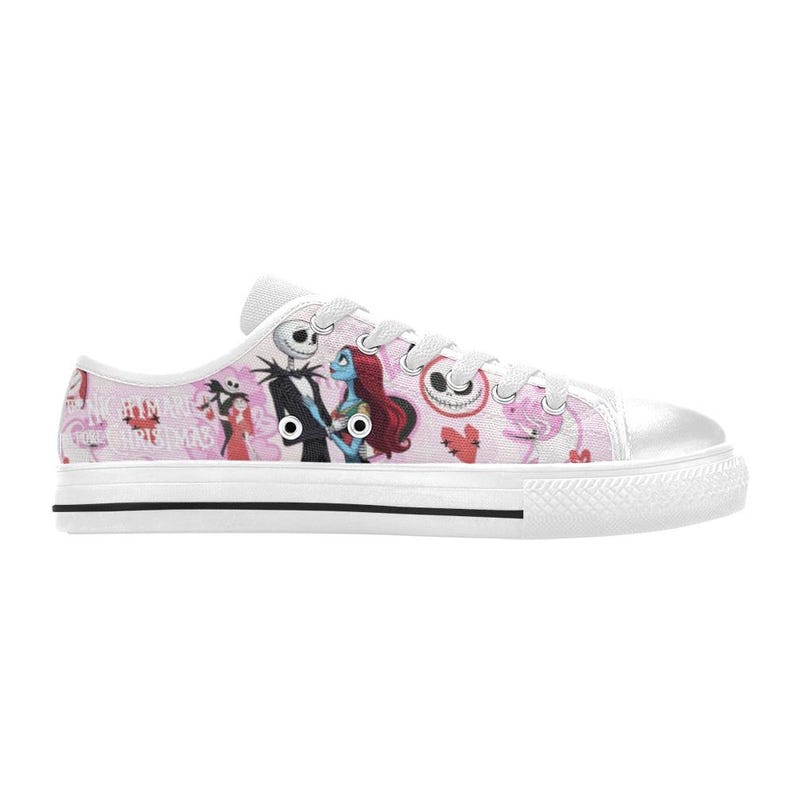 Puede incluir: Zapatillas de lona blancas con un dise&ntilde;o rosa y blanco con personajes de "Pesadilla antes de Navidad". El dise&ntilde;o incluye a Jack Skellington, Sally y otros gr&aacute;ficos tem&aacute;ticos. Los zapatos tienen cordones blancos y una franja negra en la suela.