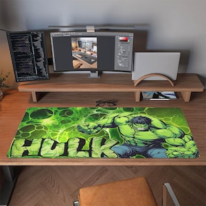Könnte beinhalten: Grünes und schwarzes Hulk-Mauspad mit dem Wort "Hulk" in großen grünen Buchstaben. Der Hulk wird in einer dynamischen Pose mit einem grünen und schwarzen Hintergrund dargestellt. Das Mauspad ist rechteckig und liegt auf einem Holzschreibtisch.