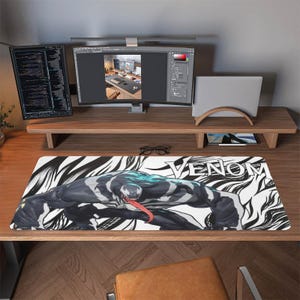 May include: A rectangular desk mat featuring the Marvel Comics character Venom. The mat has a black and white background with the word "VENOM" in white. The character is depicted in shades of black, gray, and white, with a red tongue.