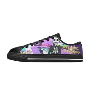 May include: Black low-top canvas sneakers featuring a colorful graphic design from "The Nightmare Before Christmas." The design includes characters like Jack Skellington and Sally, with the movie title in yellow text. The shoes have black soles and laces.