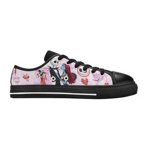 Puede incluir: Zapatillas bajas de lona con puntera, cordones y suela negros. El lateral presenta un fondo rosa con ilustraciones de personajes de "Pesadilla antes de Navidad". El dise&ntilde;o incluye a Jack Skellington, Sally y otros elementos tem&aacute;ticos.