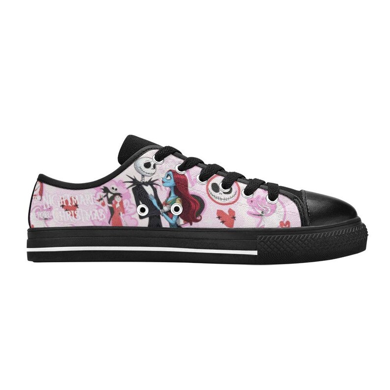 Puede incluir: Zapatillas bajas de lona con puntera, cordones y suela negros. El lateral presenta un fondo rosa con ilustraciones de personajes de "Pesadilla antes de Navidad". El dise&ntilde;o incluye a Jack Skellington, Sally y otros elementos tem&aacute;ticos.