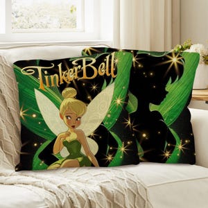 May include: Two decorative throw pillows featuring Tinker Bell. One pillow displays a full-color image of Tinker Bell in a green dress with gold accents, and the other shows a silhouette. The pillows have a black background with green leaves and gold stars, and the words "Tinker Bell" in gold.