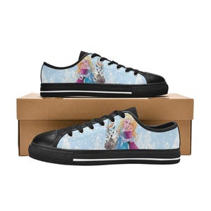 May include: Pair of blue canvas sneakers featuring a winter scene with two characters and a snowman. The shoes have black soles and laces, and are set against a light blue background with a winter forest design.