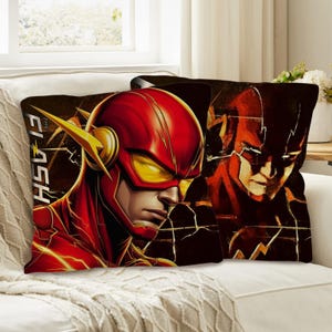 Puede incluir: Dos cojines decorativos con The Flash. Un cojín muestra una ilustración detallada de The Flash con su traje rojo y amarillo, con el texto "The Flash" en el lateral. El otro cojín muestra una imagen más abstracta del personaje.
