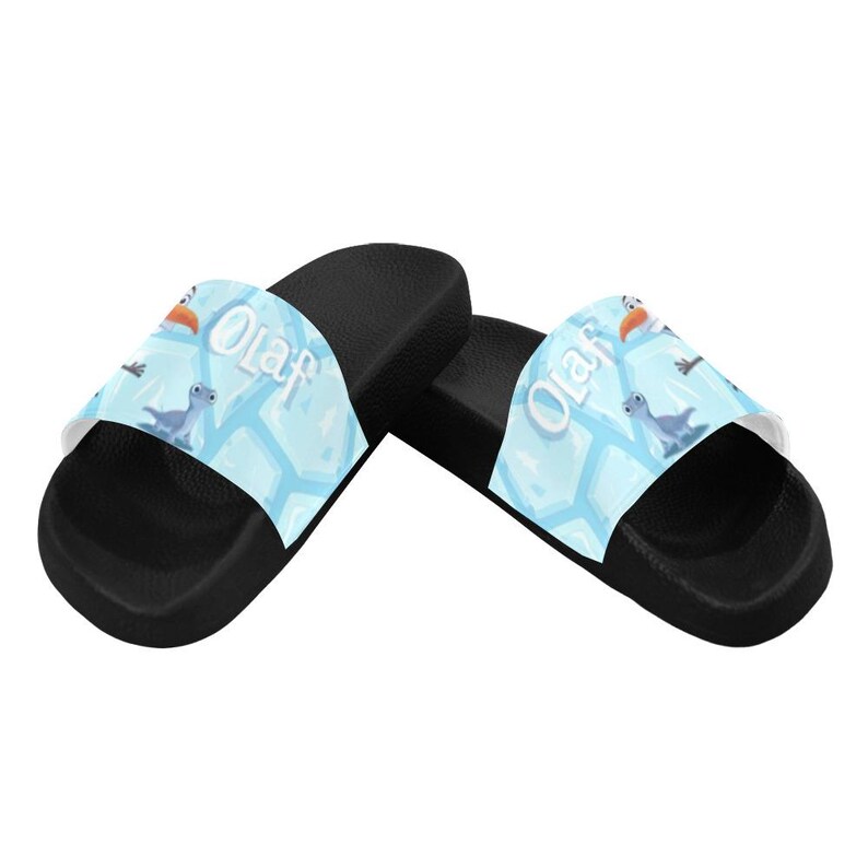 May include: Black slide sandals with a light blue strap. The strap features the word "Olaf" and cartoon images of Olaf, a bird, and a blue creature. The sandals have a black sole and a white interior.