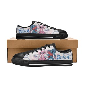 Pu&ograve; includere: Un paio di scarpe da ginnastica basse in tela con puntale e suola neri. Le scarpe da ginnastica presentano un motivo ripetuto di personaggi dei cartoni animati in rosa e blu, con la scritta "Stitch" stampata sul lato.