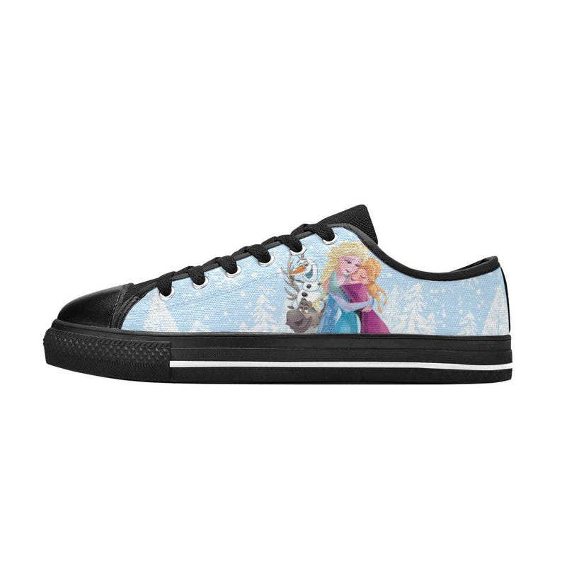 May include: Light blue canvas sneakers featuring a black toe cap and black laces. The side of the shoe displays a winter scene with Elsa, Anna, and Olaf from the movie Frozen. The sole is black with a white stripe.
