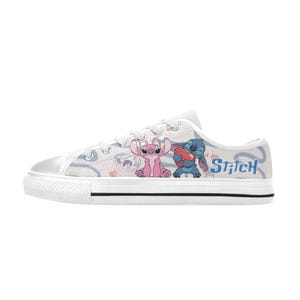 Pu&ograve; includere: Scarpe da ginnastica in tela bianca con un design a cartoni animati di Stitch e Angel. Le scarpe hanno un design a taglio basso con suola e lacci in gomma bianchi. Il design include la parola "Stitch" in blu.