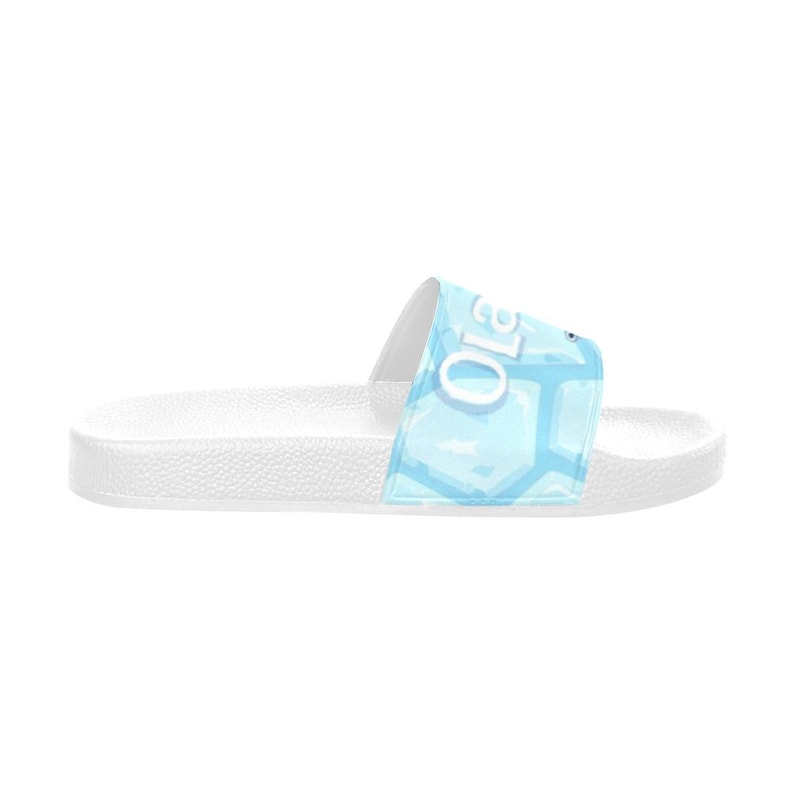 May include: White slide sandal with a light blue geometric pattern on the strap. The strap features the word "Ola" in white. The sandal is designed for casual wear and is suitable for indoor or outdoor use.