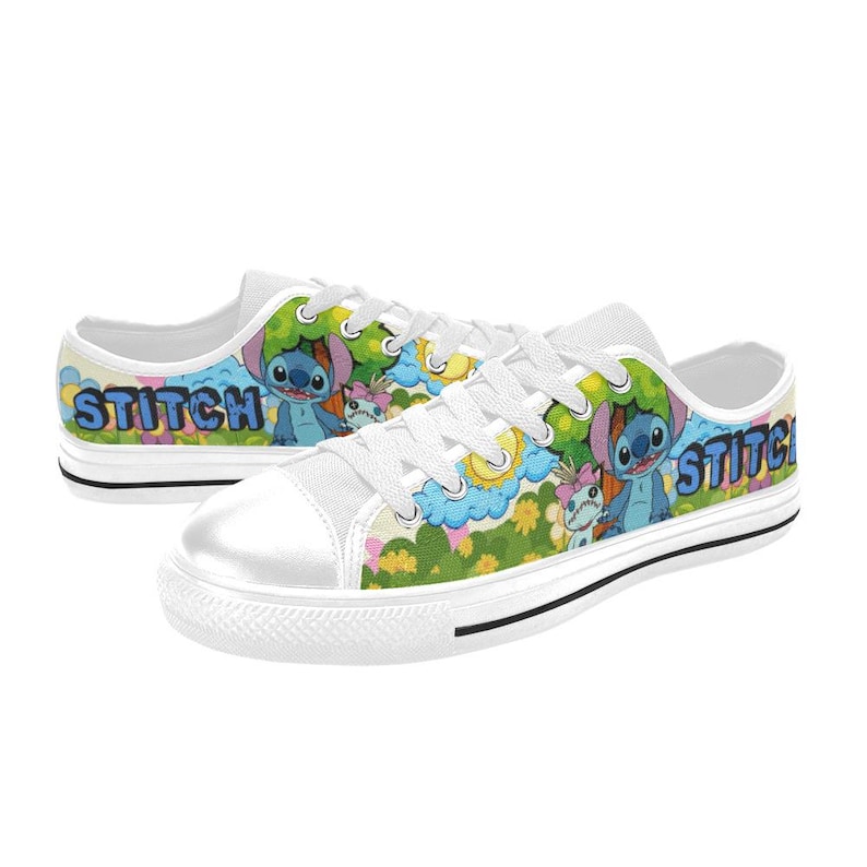 May include: White canvas trainers with a colourful cartoon design. The shoes feature the word "Stitch" in blue and yellow, alongside images of the character Stitch and other characters in a vibrant outdoor scene.