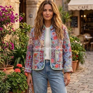 May include: A light blue quilted jacket featuring a vibrant floral pattern in shades of red, pink, and green, with a white base layer and blue denim jeans. The jacket has two front pockets and light green trim along the edges and cuffs.