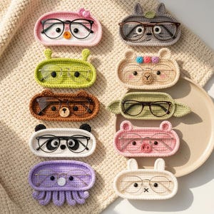 Può includere: Una collezione di dieci portaocchiali ovali all'uncinetto, ognuno caratterizzato da un design unico con volto di animale o personaggio. Questi supporti sono realizzati con vari filati colorati e includono dettagli ricamati, con occhiali appoggiati sopra.