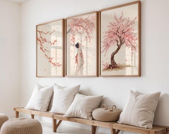 Può includere: Tre stampe artistiche incorniciate a tema giapponese. Le stampe raffigurano fiori di ciliegio e una donna in kimono. Le cornici sono di colore marrone chiaro e l'opera d'arte ha uno stile acquerello morbido. Le stampe sono esposte sopra una panca di legno con cuscini.