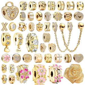 Puede incluir: Una colección de abalorios dorados con varios diseños, incluyendo corazones, flores y formas geométricas. Algunas cuentas están adornadas con cristales transparentes. Los abalorios son para pulseras y collares.