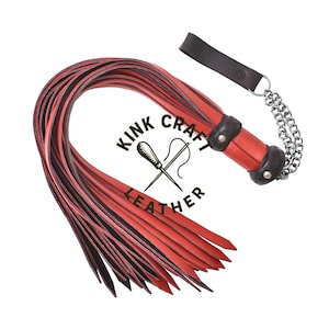 May include: Red and black leather flogger with a black handle and silver chain. The flogger has multiple leather falls and the text "KINK CRAFT LEATHER" is visible.