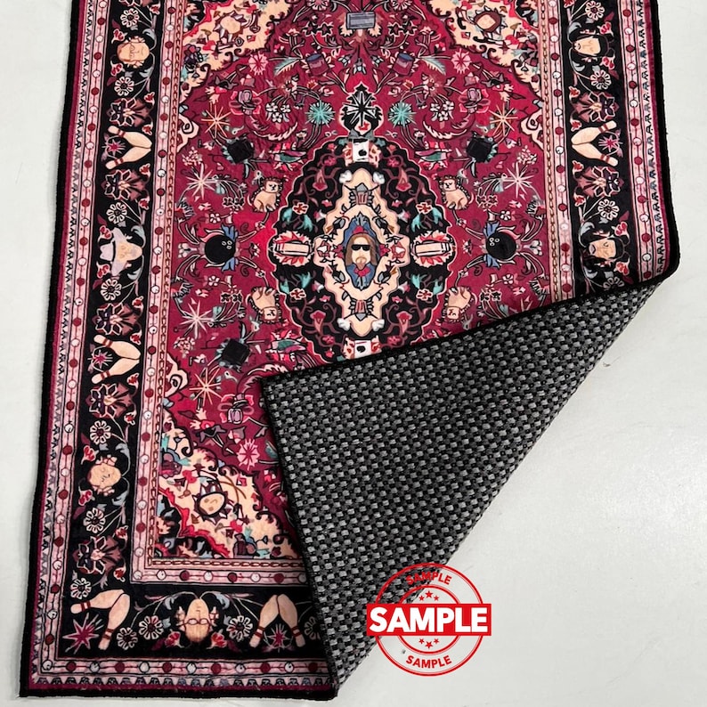 May include: A rectangular rug with a detailed, ornate design in shades of red, black, and cream. The pattern includes floral and geometric elements, with a black border. The rug's underside is a textured gray material. A red "SAMPLE" stamp is visible.