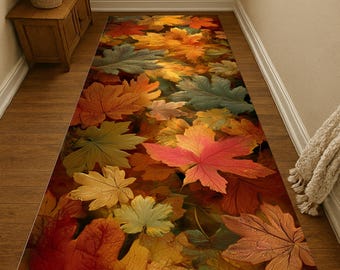 Puede incluir: Una alfombra rectangular con un diseño de hojas de otoño vibrantes. La alfombra presenta hojas de arce coloridas en tonos rojos, naranjas, amarillos y verdes, creando una estética cálida y acogedora. La alfombra está colocada sobre un suelo de madera.