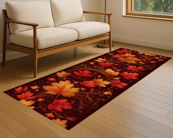 Puede incluir: Una alfombra rectangular con un fondo burdeos oscuro, adornada con un patrón de hojas de otoño estilizadas en tonos rojos, naranjas y amarillos. Las hojas están dispuestas en un diseño fluido y orgánico.