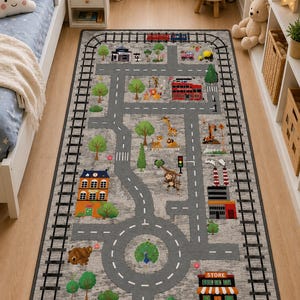 May include: A gray children's play rug with a road and train track design. The rug features a road network with buildings, trees, and a roundabout. Colorful illustrations of vehicles and animals are scattered throughout the design.