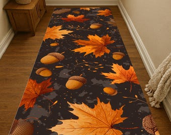 Puede incluir: Una alfombra rectangular con un diseño otoñal. La alfombra muestra grandes hojas de arce naranjas y bellotas dispersas sobre un fondo gris oscuro. El diseño evoca una estética otoñal, adecuada para pasillos o entradas.