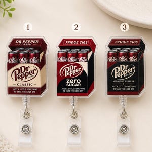 May include: Three badge reels featuring miniature Dr Pepper packaging designs. The first is Dr Pepper Classic, the second is Dr Pepper Zero Sugar, and the third is Dr Pepper Midnight Reserve. Each includes a retractable cord and a clear plastic strap.