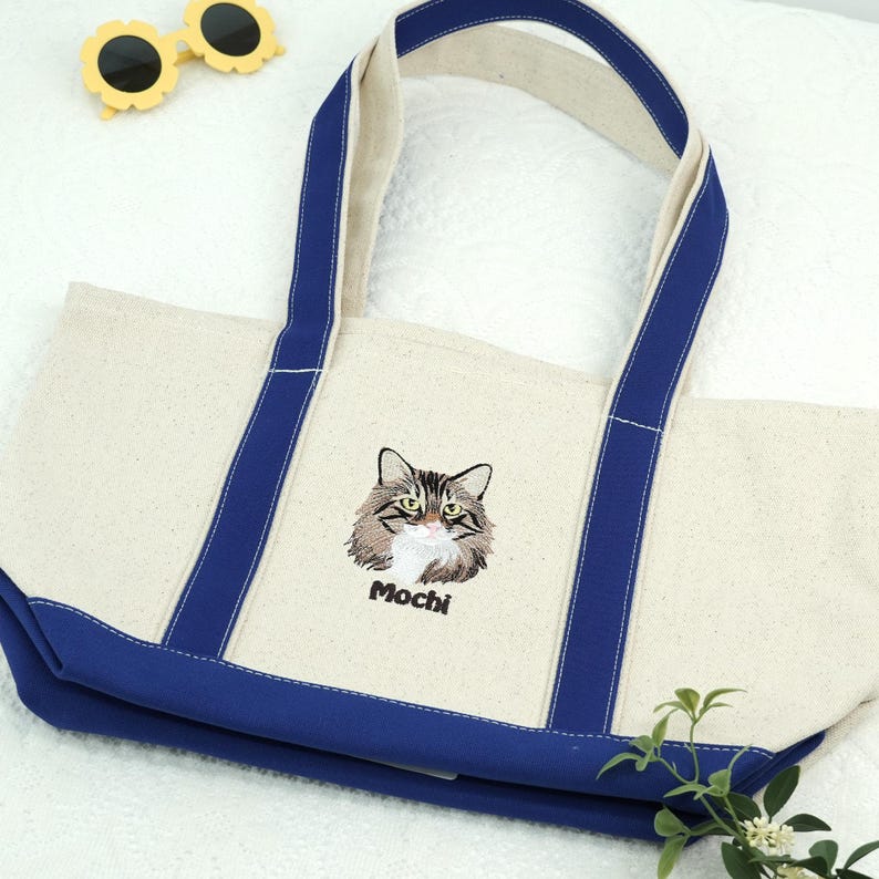 Natural/Royal Bags 8871 Boat Tote featuring a custom embroidered cat portrait with the name "Mochi." Styled with yellow sunglasses, this personalized cat lover tote is a vibrant and sturdy custom canvas bag for summer vacations and daily errands.