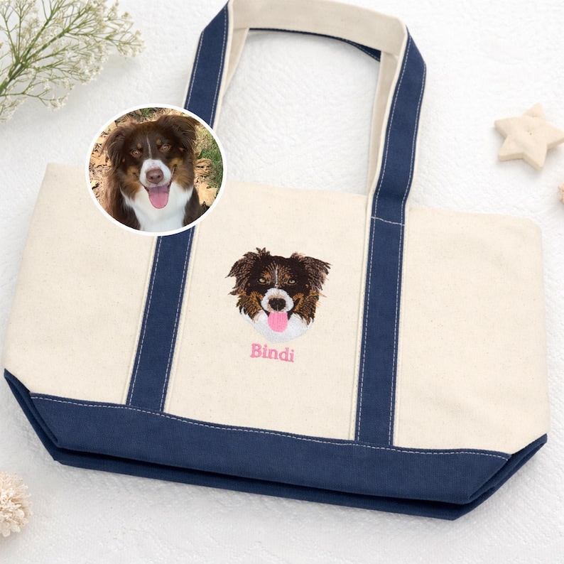 NATURAL/Navy Bags 8871 Boat Tote featuring a custom pet portrait embroidery of an Australian Shepherd. The image shows the transition from a real dog photo to high-quality personalized embroidery with the name "Bindi." A perfect custom dog mom gift and durable canvas beach bag.