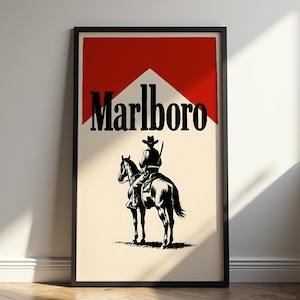 May include: Framed poster featuring the Marlboro logo with a cowboy on horseback. The logo is in black text over a white background, with a red triangle at the top. The cowboy and horse are black silhouettes.