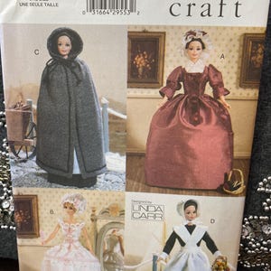 May include: Vogue Craft pattern 7039 featuring doll clothing designs. The pattern includes four doll outfits: a gray hooded cape, a burgundy gown, a pink and white dress, and a black and white maid outfit. The pattern is designed by Linda Carr.