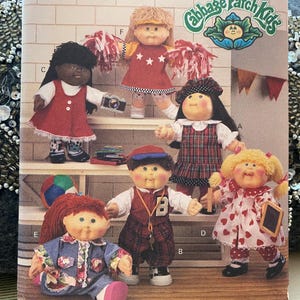 May include: A vintage Cabbage Patch Kids pattern featuring six dolls in various outfits. The dolls have different hairstyles and skin tones. The background includes a shelf, a colorful ball, and the Cabbage Patch Kids logo.