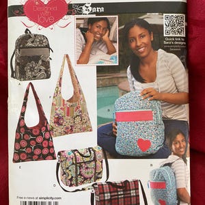May include: A Simplicity 1823 sewing pattern envelope featuring designs for various bags including backpacks, hobo bags, and messenger bags. The cover displays illustrations and photographs of finished bags with floral, plaid, and paisley patterns.
