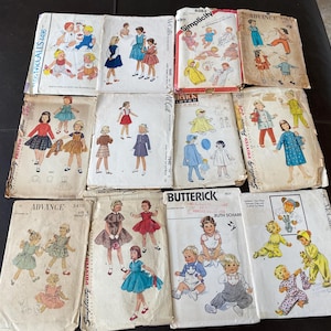 May include: A collection of vintage sewing patterns for children's clothing. The patterns feature illustrations of dresses, coats, and other garments. The covers are in various colors and styles, with brand names like Simplicity and McCall's.