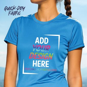 May include: A light blue, short-sleeved athletic shirt with the text "ADD YOUR DESIGN HERE" in a white box. The words "QUICK-DRY FABRIC" are printed on the upper left. The shirt is made of a smooth, lightweight material.