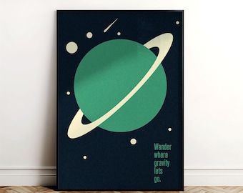 May include: A framed art print showing a green planet with a cream ring on a dark blue backdrop. The print has the text "Wander where gravity lets go." Decorative wall art for the home.