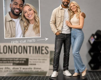 May include: A custom-made figurine of a couple, standing on a black base. The man wears a tan jacket and black pants, while the woman wears a cream top and blue jeans. The image includes a photo of the couple and text that reads "FROM YOUR PHOTO" and "LONDONTIMES".
