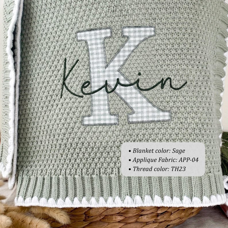 May include: A sage green knit blanket featuring a large letter K in a white and gray gingham check pattern. The name Kevin is embroidered in dark green cursive script across the letter. The blanket has a white ribbed border with a scalloped edge.