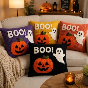 Puede incluir: Cuatro cojines cuadrados de ganchillo en colores morado, amarillo, naranja y negro. Cada cojín presenta una calabaza naranja, un fantasma blanco y el texto blanco "BOO!" cosido en la parte frontal. Los diseños son iguales en los cuatro.