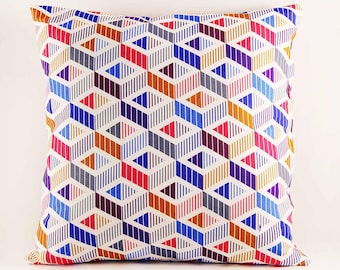 May include: A square throw pillow featuring a repeating geometric pattern of diamonds and cubes. The design consists of vertical lines in vibrant colors including red, blue, purple, orange, and pink, creating a multi-dimensional visual effect.