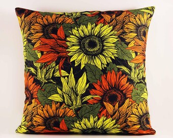 May include: A square throw pillow featuring a dense, repeating pattern of sunflowers in vibrant shades of yellow, orange, and deep red, interspersed with dark green leaves against a solid black background, creating a bold floral display.