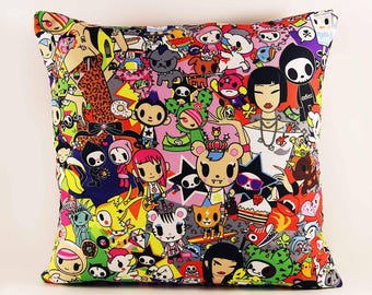 May include: A square throw pillow featuring a vibrant, multi-colored all-over print of various cartoon characters, including stylized figures, animals, and food items. The design incorporates bold shades of pink, yellow, blue, and black.