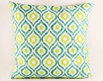 May include: A square throw pillow featuring a repeating geometric ikat pattern in shades of bright lime green, teal, and white. The design consists of interconnected, elongated diamond shapes with soft, blurred edges across the entire surface.