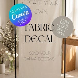 May include: A vertical off-white fabric banner suspended on a black metal stand with sage green ribbon ties. The text reads: CREATE YOUR OWN FABRIC DECAL, SEND YOUR CANVA DESIGNS, SEND VIA CANVA EVE & GRACE, and TURN YOUR DESIGN INTO VINYL.