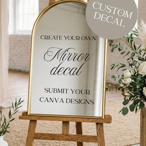 May include: A gold-framed mirror with an arched top is displayed on a wooden easel. The mirror's surface reflects the surrounding environment. Text on the mirror reads "Create Your Own Mirror Decal" and "Submit Your Canva Designs." A circular graphic says "Custom Decal."
