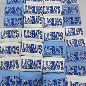May include: A collection of folded light blue and white t-shirts arranged in a grid. Each shirt features the word LASHAYS printed in a bold, block-style font with a blue and white patterned design, including polka dots and stripes.